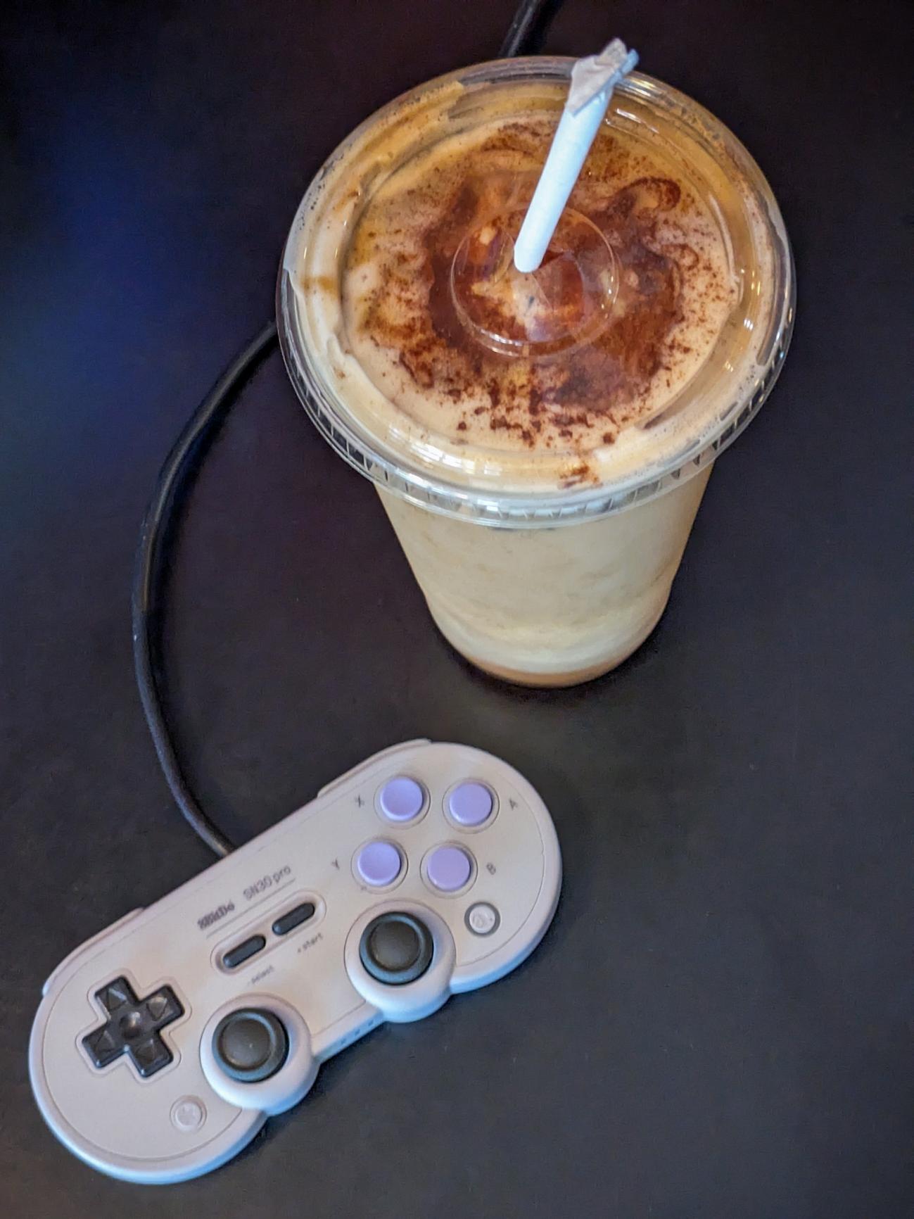 An iced Chai Latte next to a game controller