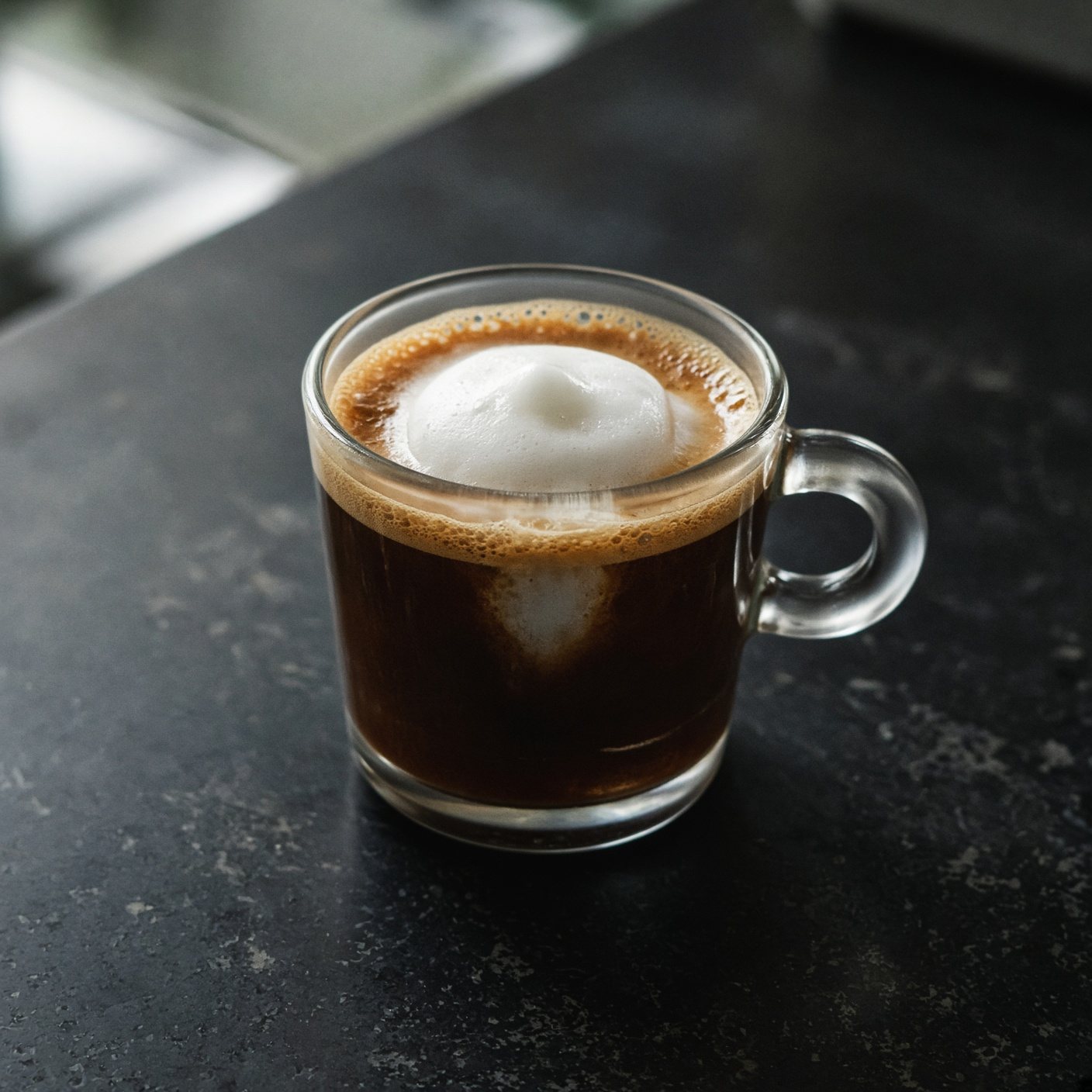 An espresso macchiato marked with a dollop of foam