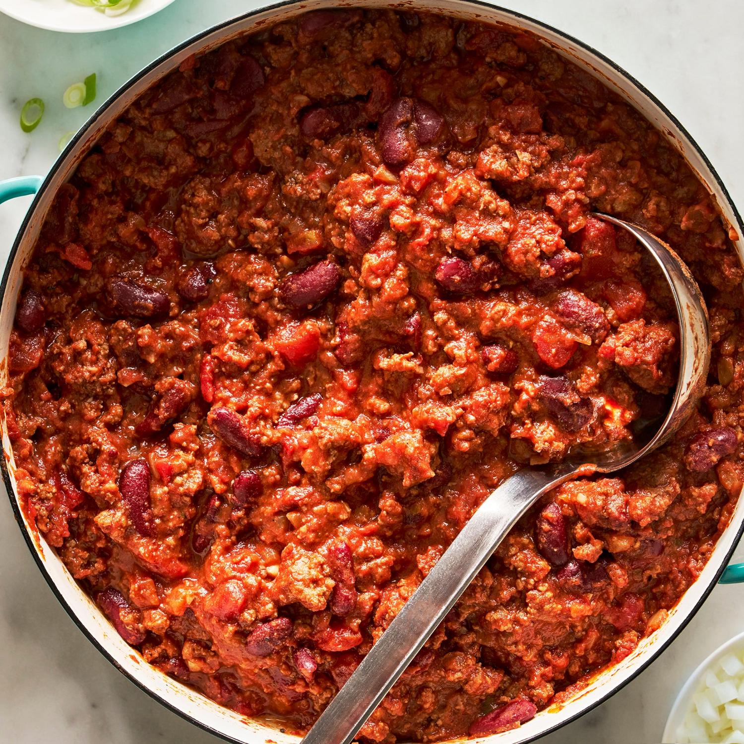 A pot of chili with beans and a ladle