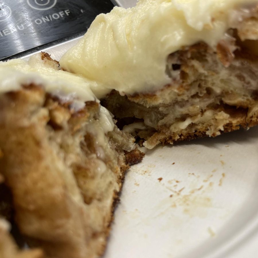 A cinnamon roll pulled apart, with cream cheese frosting